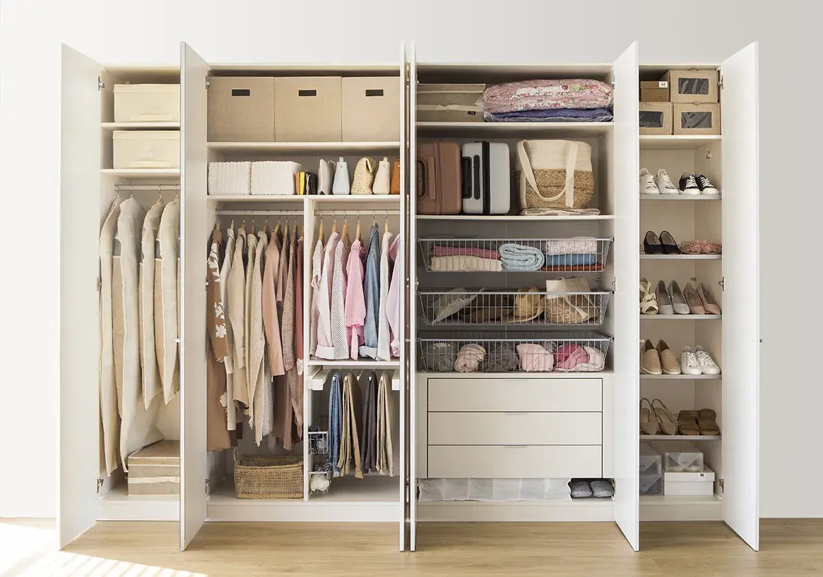 Armario organizado con ropa colgada y doblada, cestas y cajas, siguiendo el método Marie Kondo para un espacio ordenado y funcional.