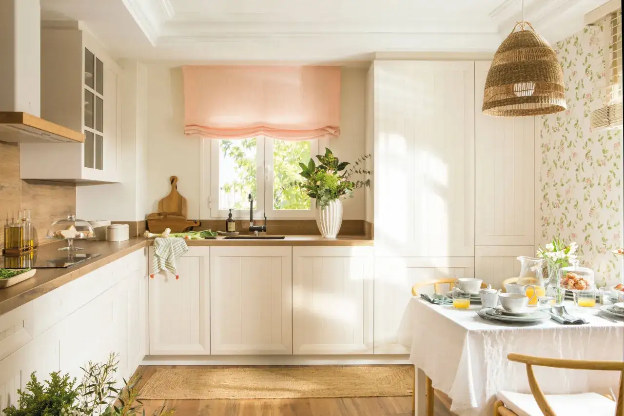 Encantadora decoracion cocinas con muebles blancos, encimera de madera y un juego de mesa listo para el desayuno.