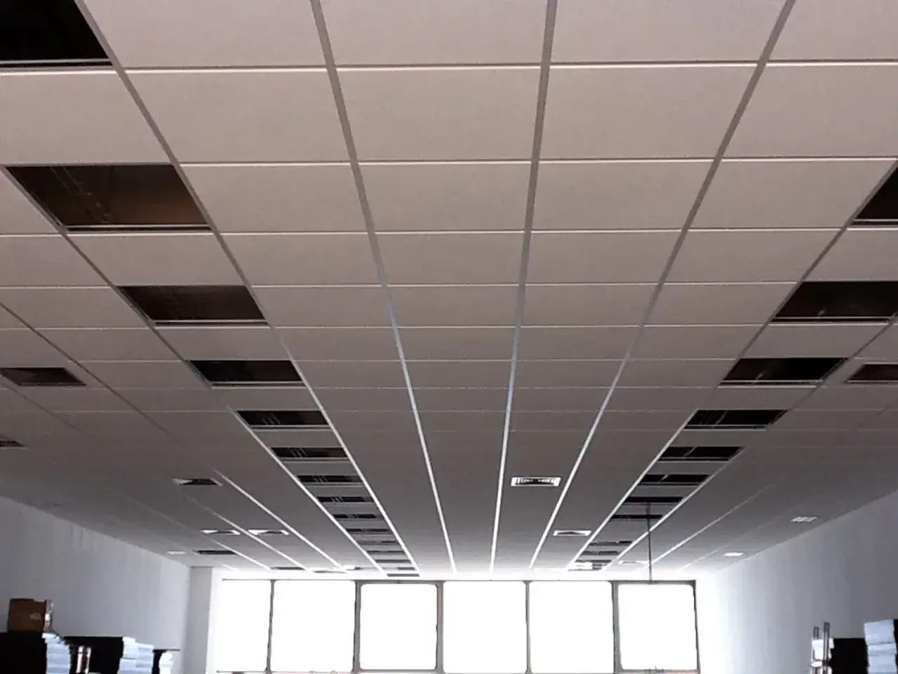 Falso techo pladur con paneles modulares y huecos para iluminación o ventilación.
