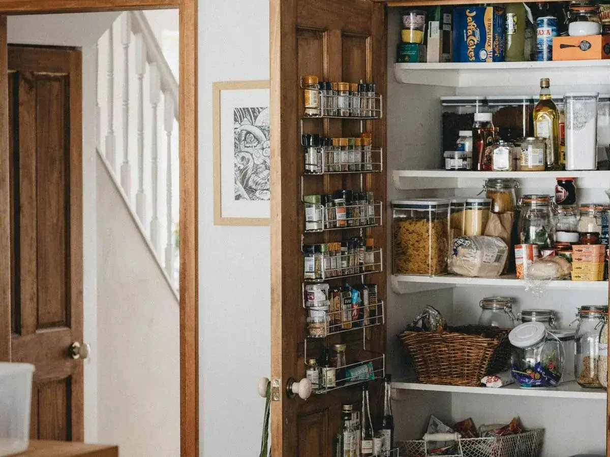 Estanterías llenas de especias y alimentos para organizar cocina. Cestas y frascos de vidrio para mantener todo en orden.
