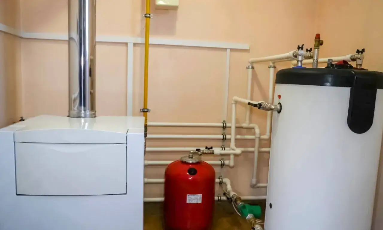 Instalación de sistema de calefacción con caldera de gas, acumulador de agua caliente y depósito de expansión rojo.