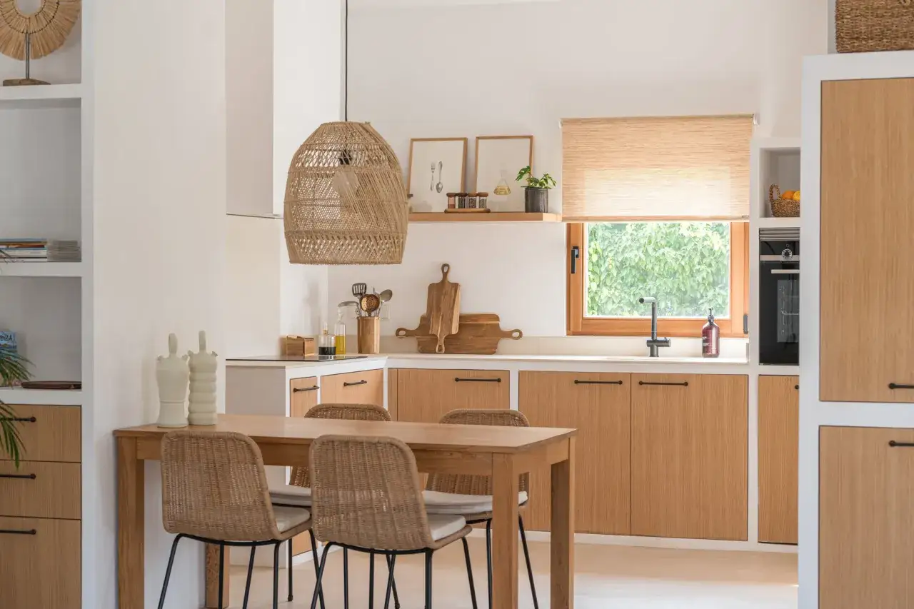 Mesa de cocina de madera con sillas de ratán. La decoración de la mesa incluye jarrones blancos y un centro de mesa rústico.