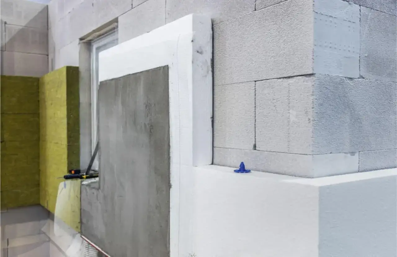 Detalles de la construcción de una pared exterior con materiales aislantes como lana de roca y poliestireno expandido, listos para recibir el revestimiento.