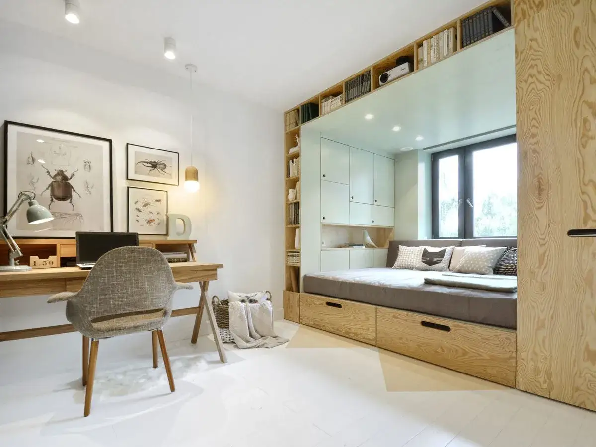 Acogedor dormitorio juvenil con cama empotrada, escritorio de madera y estanterías llenas de libros.