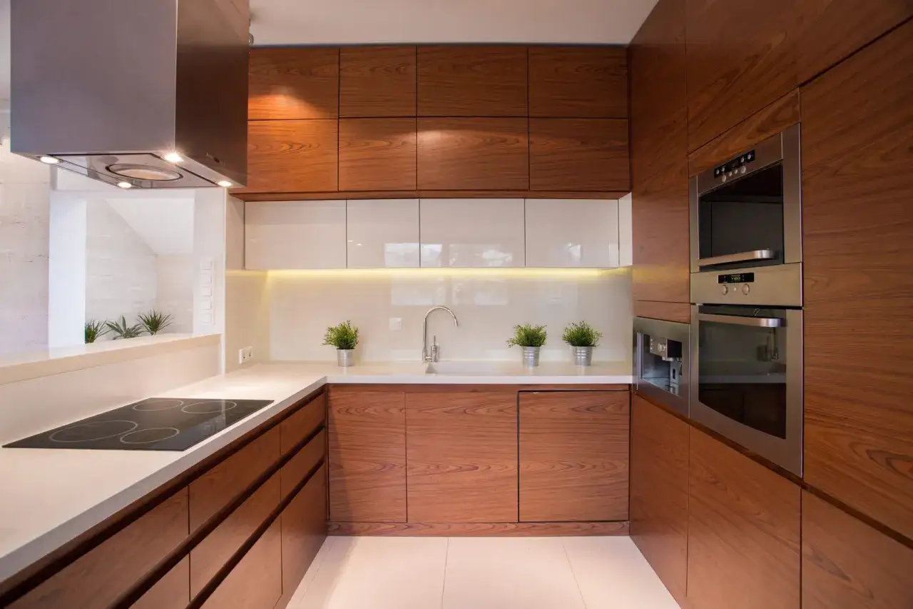 Cocinas pequeñas y bonitas con gabinetes de madera y encimeras blancas. Incluye estufa, fregadero, horno y cafetera.