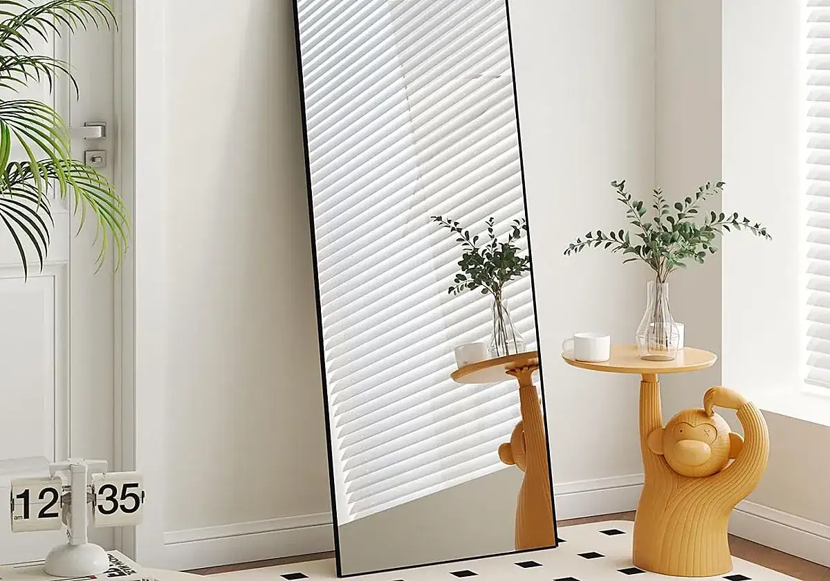 Espejo de cuerpo entero junto a una planta y una mesa auxiliar con forma de mono. Ideas de donde colocar espejos en el salón.