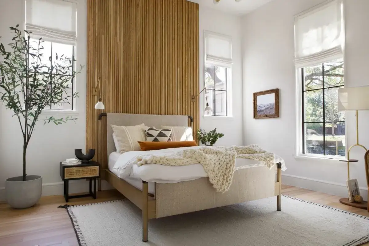 Ideas dormitorio matrimonio: cama tapizada, pared de lamas de madera, plantas y luz natural.