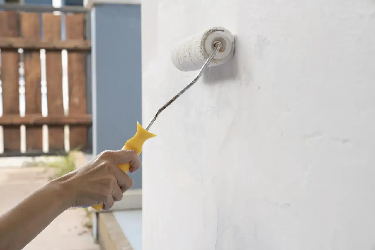 Mano aplicando imprimación a una pared con rodillo. El proceso de imprimación pintura pared es clave para un buen acabado.