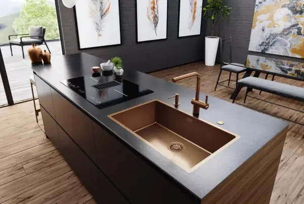 Cocina moderna con isla, placa de inducción y fregadero de cobre. Varios tipos de fregaderos, como este de diseño, realzan la estética.