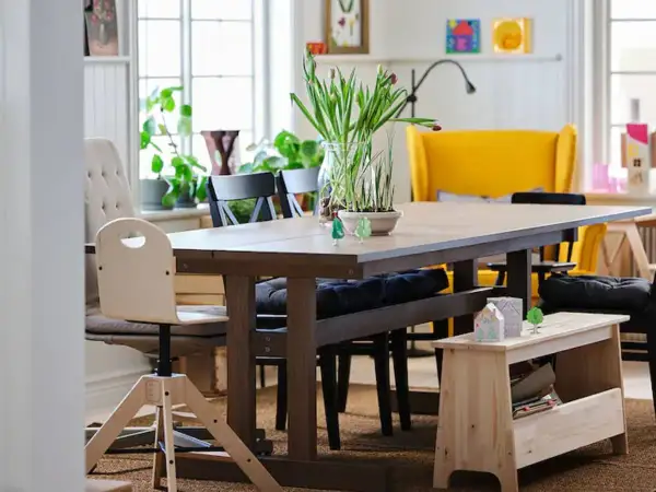 Un banco almacenaje de madera clara, perfecto para guardar libros y objetos, complementa la mesa de comedor.
