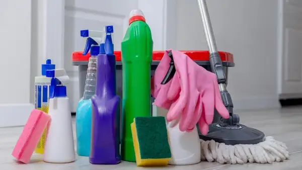 Un surtido de 25 productos de limpieza del hogar, incluyendo botellas rociadoras, esponjas, guantes rosas y un trapeador, listos para dejar tu casa reluciente.