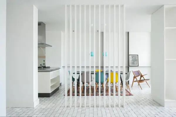 Elegante divisor vertical para dividir salón en dos ambientes, separando la cocina de la zona de comedor con sillas de colores.