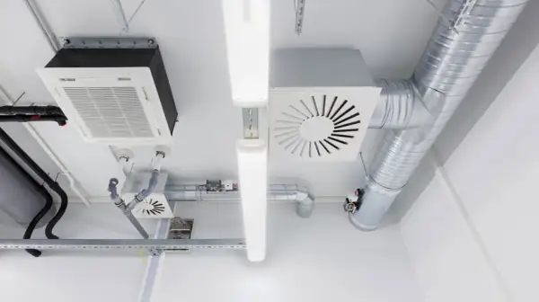 Sistema de ventilación mecánica para vivienda con conductos metálicos, unidades de aire acondicionado y luces LED en el techo.