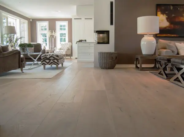 Amplio salón con chimenea y muebles elegantes, destacando los diversos tipos de parquet de madera clara que cubren el suelo.