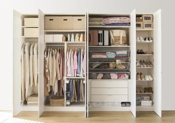 Armario organizado con ropa colgada y doblada, cestas y cajas, siguiendo el método Marie Kondo para un espacio ordenado y funcional.