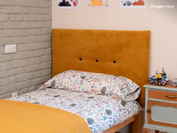 Cabecero tapizado en pana mostaza, ideal para aprender como tapizar un cabecero. Cama con ropa de cama infantil y mesita de noche.