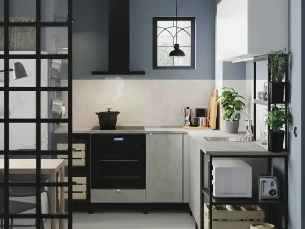Cocina estrecha y pequeña con electrodomésticos modernos, plantas y una ventana con rejas.