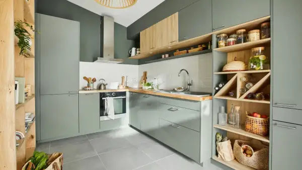 Moderna cocina verde y madera con estanterías abiertas llenas de botellas, cestas y tarros.